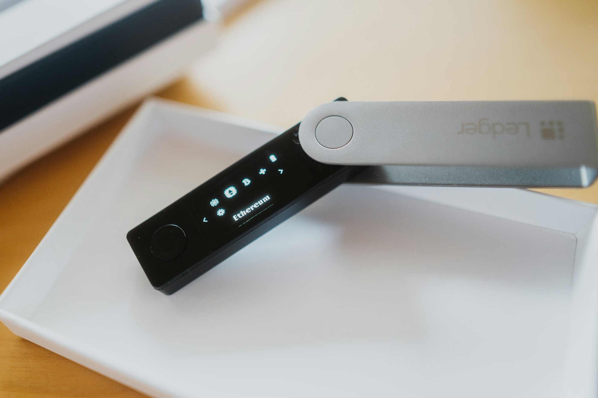 A hardware wallet in its open box on a wooden desk