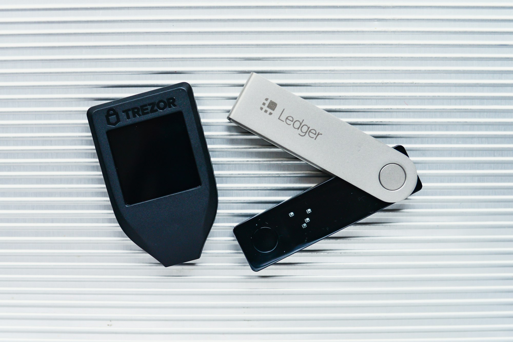 A Trezor and a Ledger hardware wallet side by side